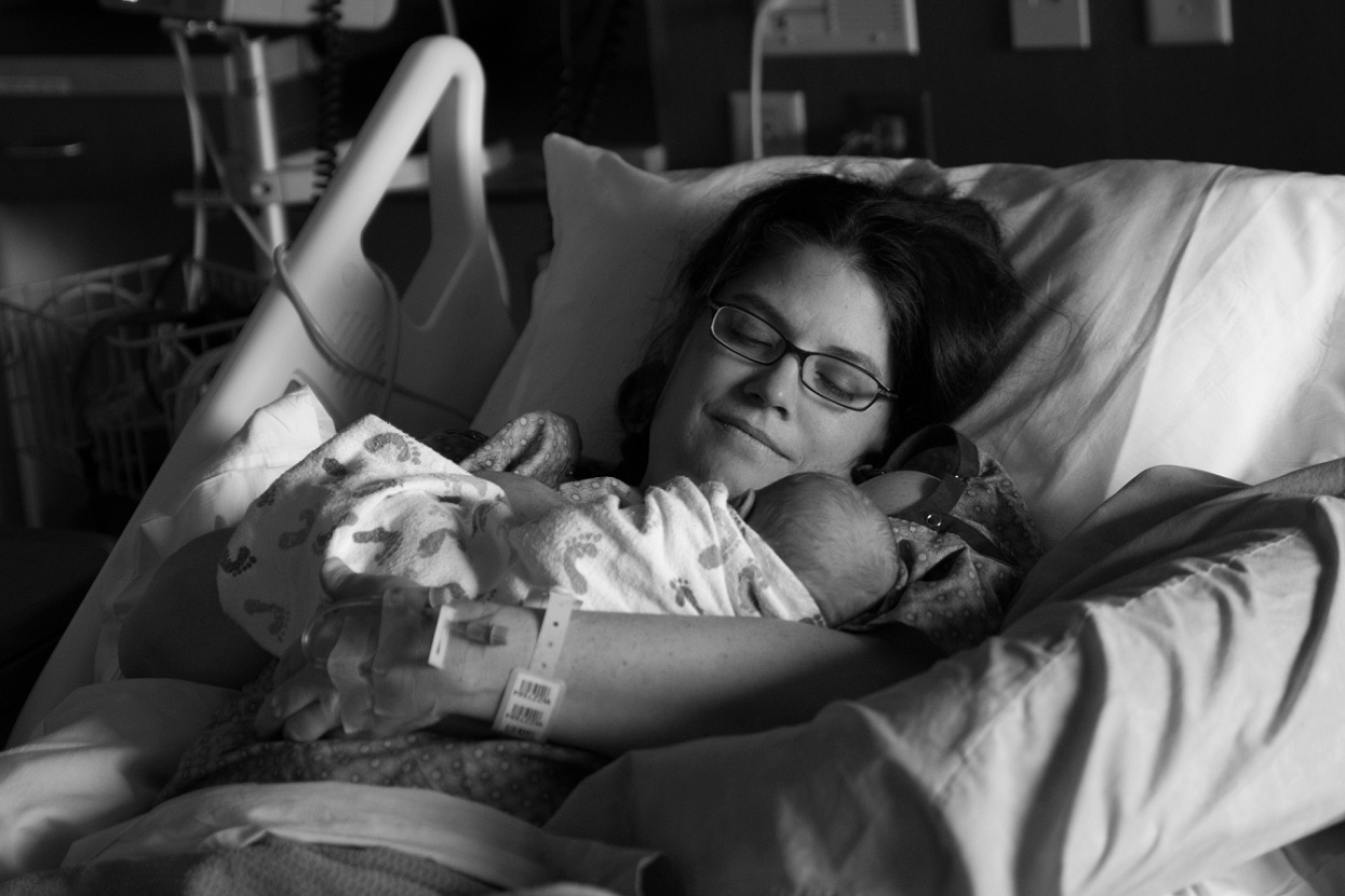 Mom holding baby in hospital bed, Wheat Ridge birth photography