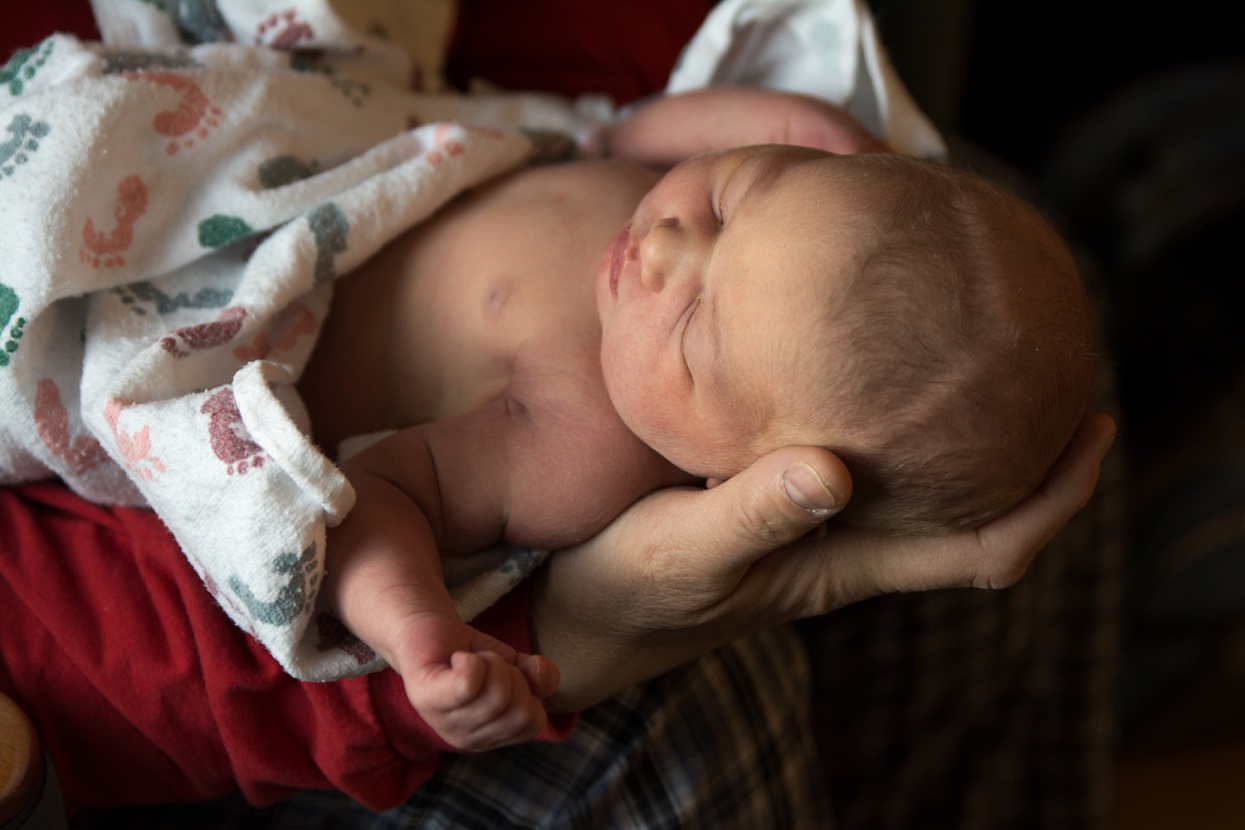 Holding newborn baby's head in hands, cradling newborn