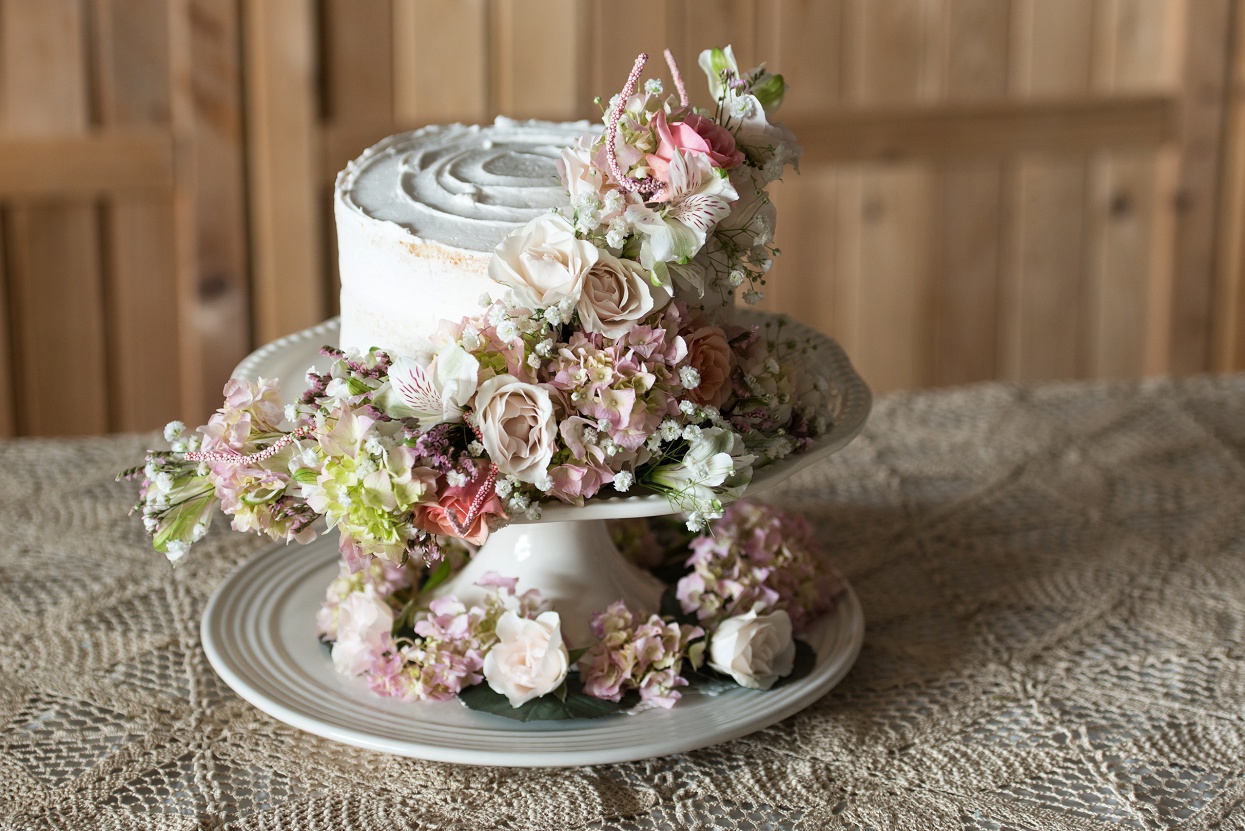Buttercream wedding cutting cake with a trail of flowers in shades of white and pink