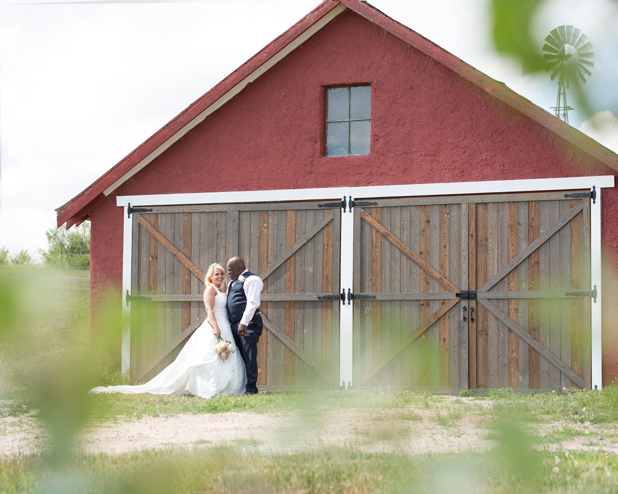 Bride and groom posing in front of a red barn, Colorado farm wedding