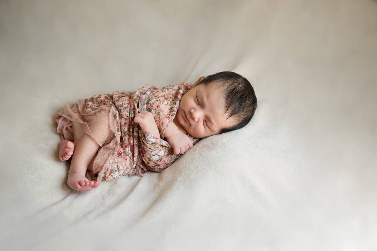 Baby in a floral wrap on a neutral background