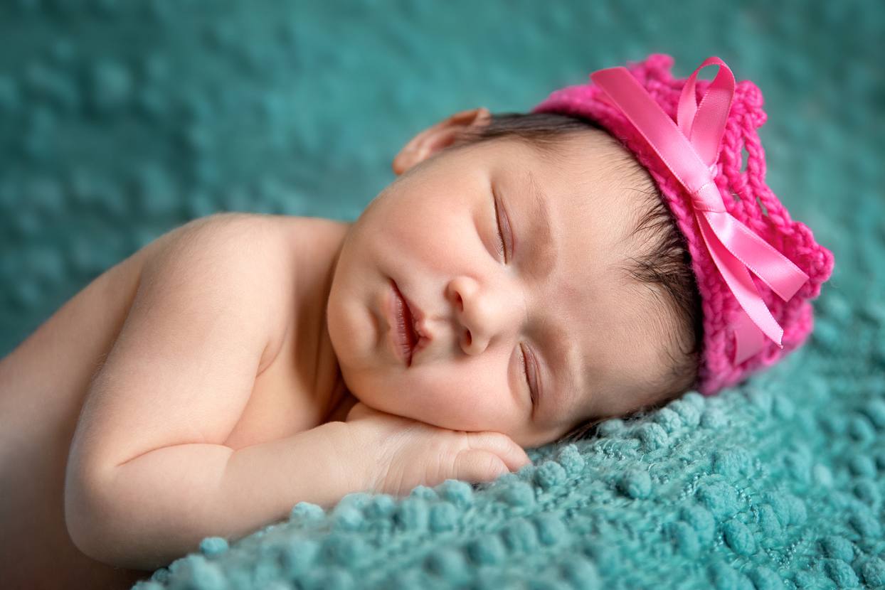 Newborn with hot pink crown and a turquoise backdrop
