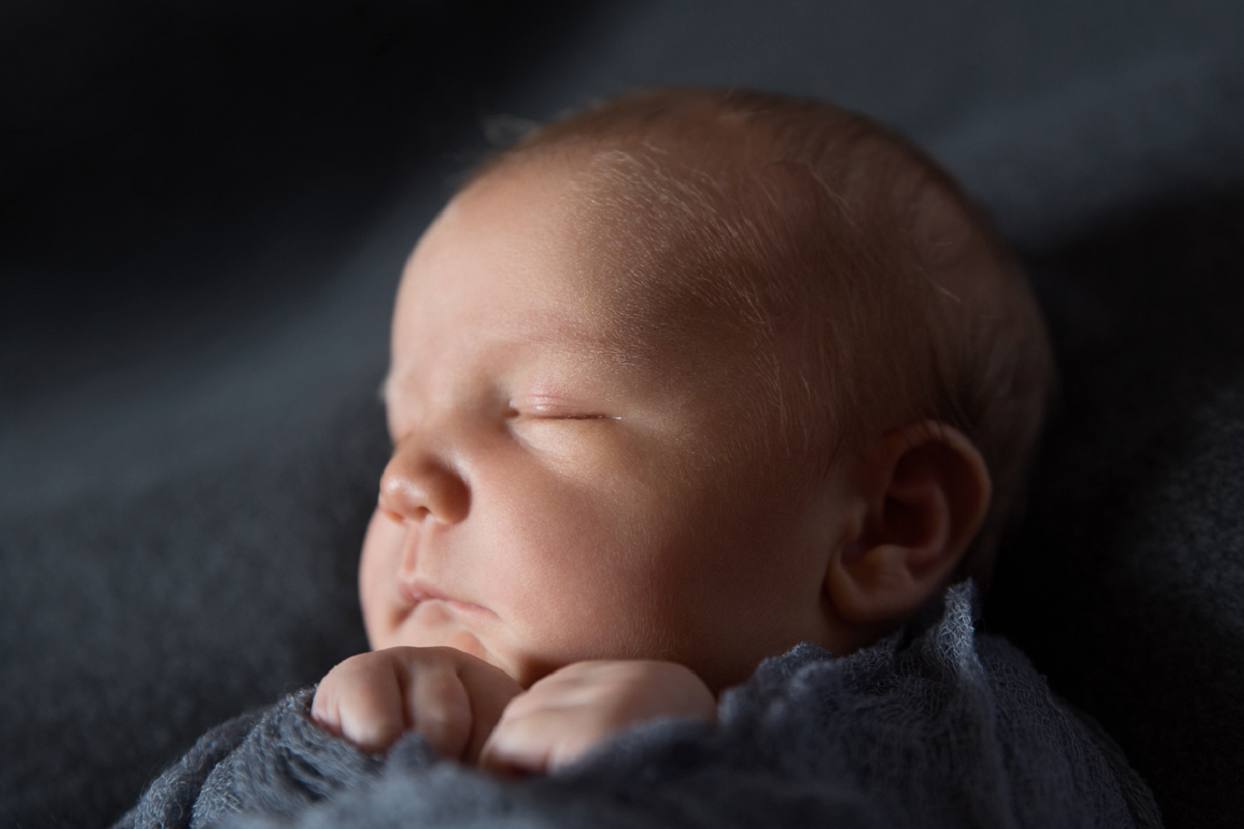 Closeup of newborn baby with soft lighting and deep shadows