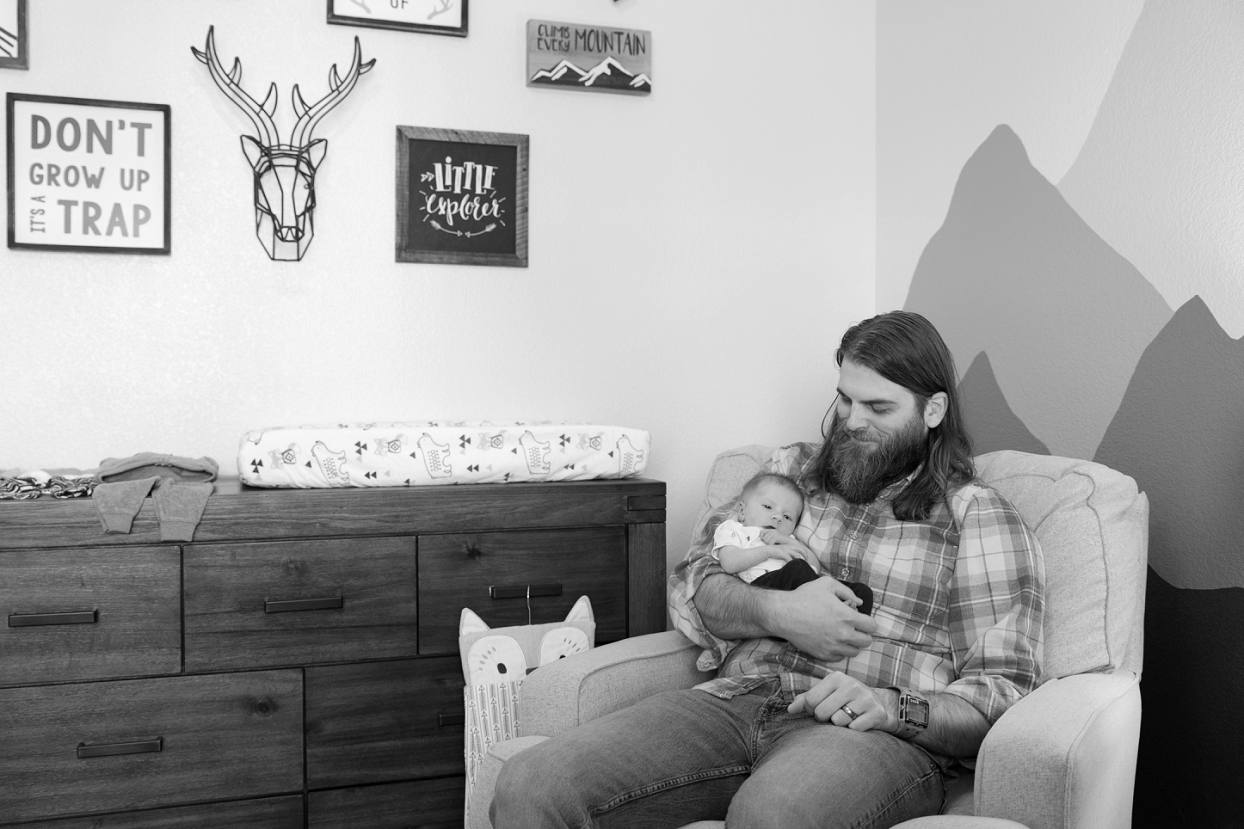 Dad holding baby in rocking chair, candid lifestyle newborn photography