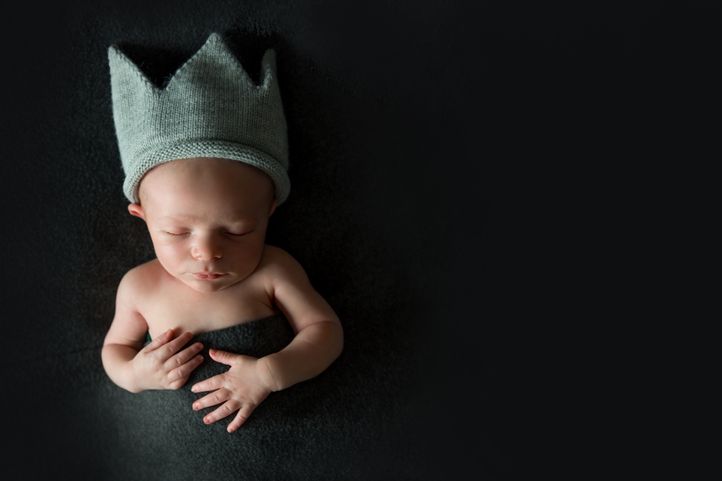 Newborn in a grey crown on a dark grey backdrop