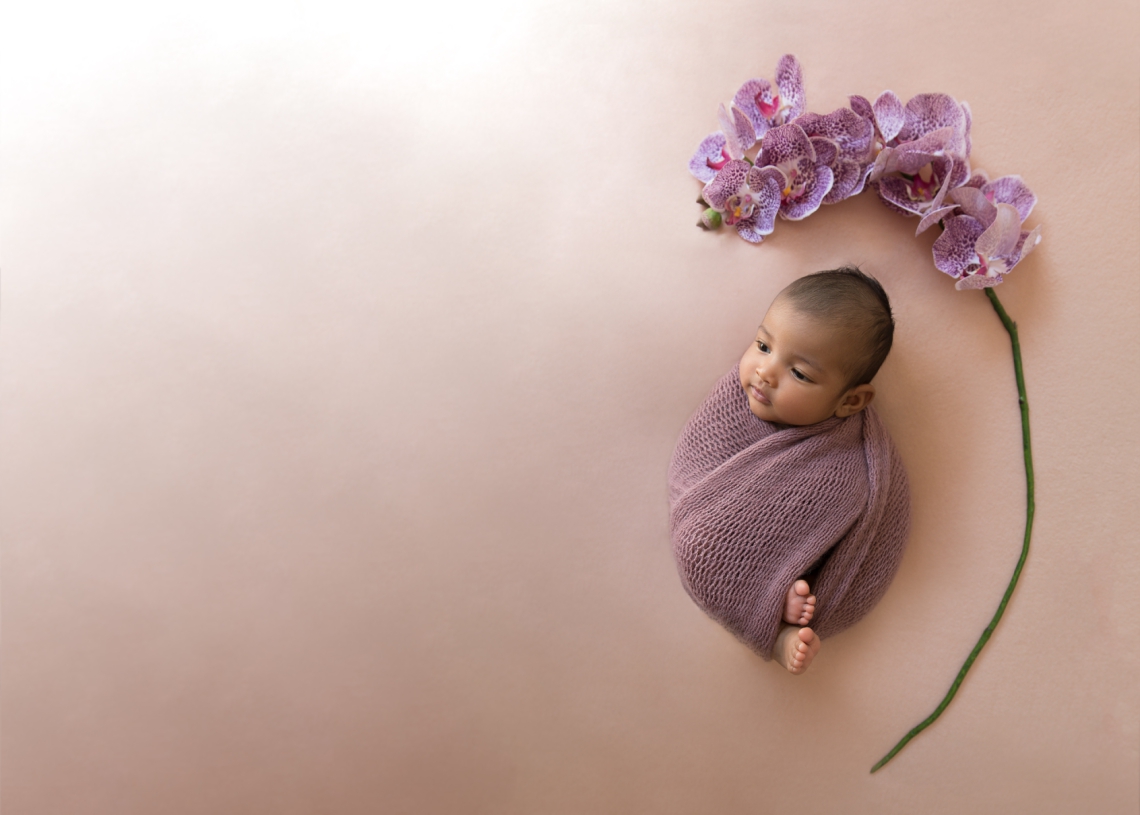 Indian baby girl with dusty purple wrap and purple orchids