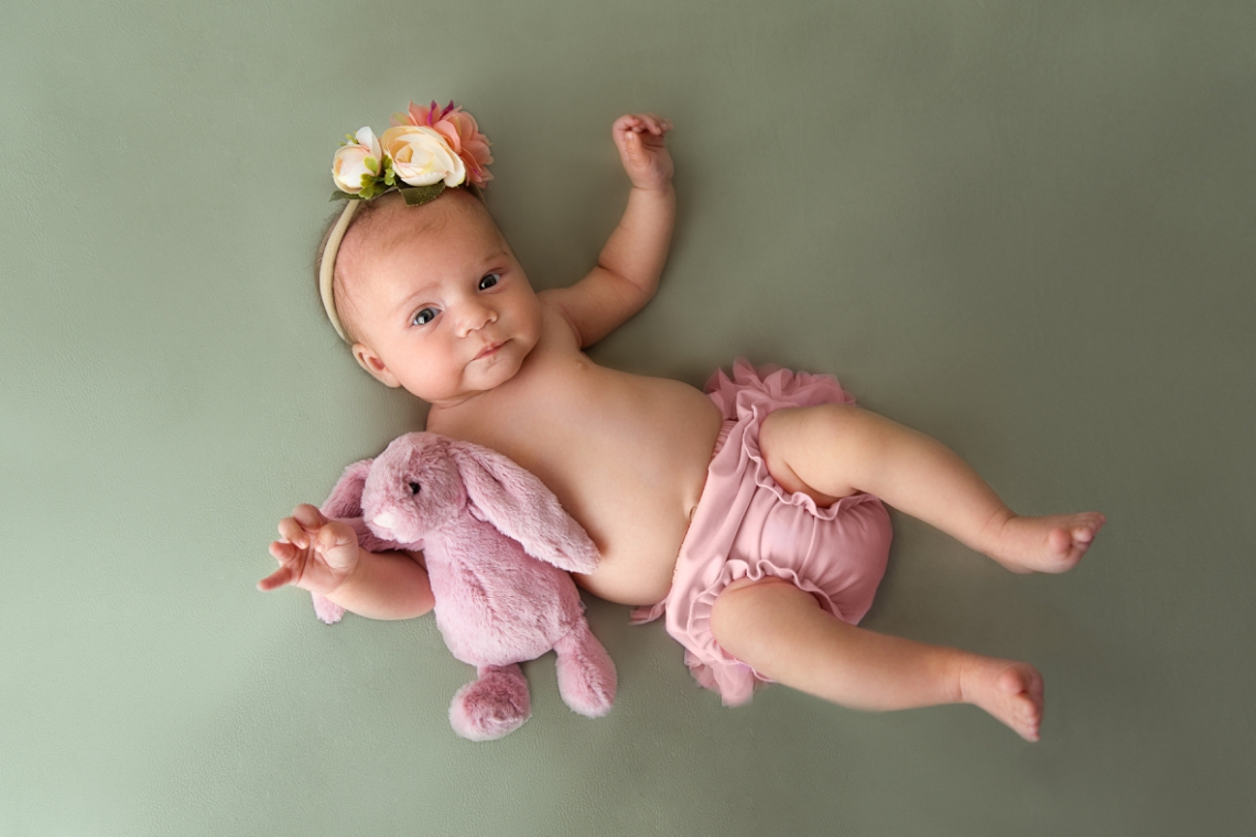 Baby girl on sage green backdrop newborn photography