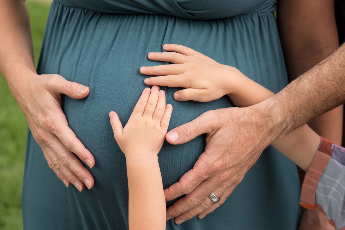 Maternity photo with kids hands on mom's belly, family hands on pregnant tummy