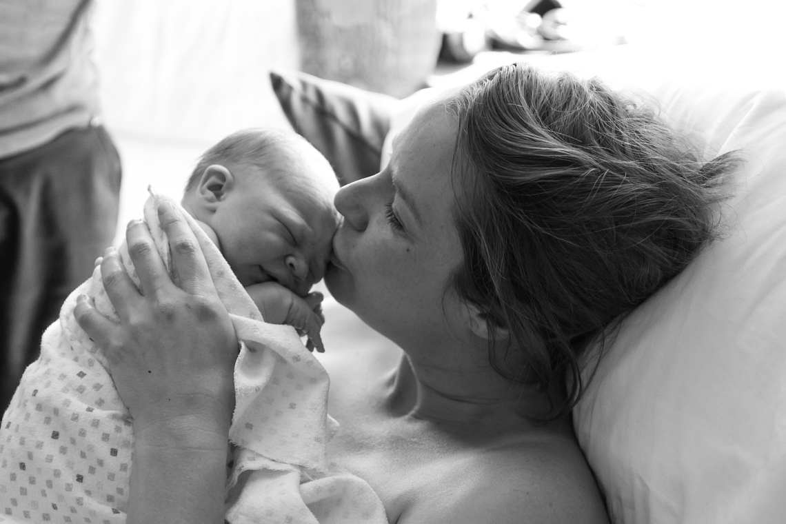 Mom kissing baby on head birth photography