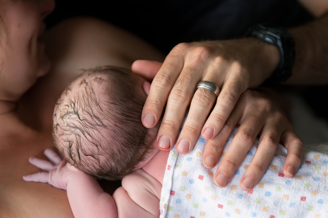 Parent's hands on a newborn baby