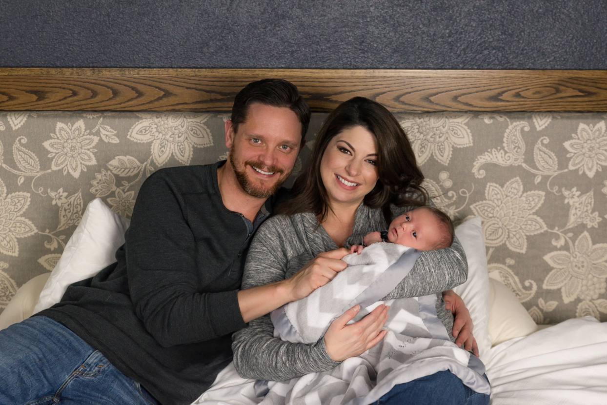 Family poses for lifestyle newborn photos on bed