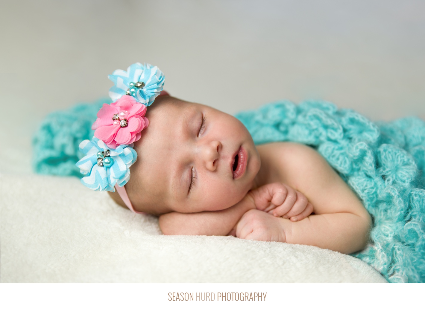 Newborn girl with long eyelashes in turquoise and pink
