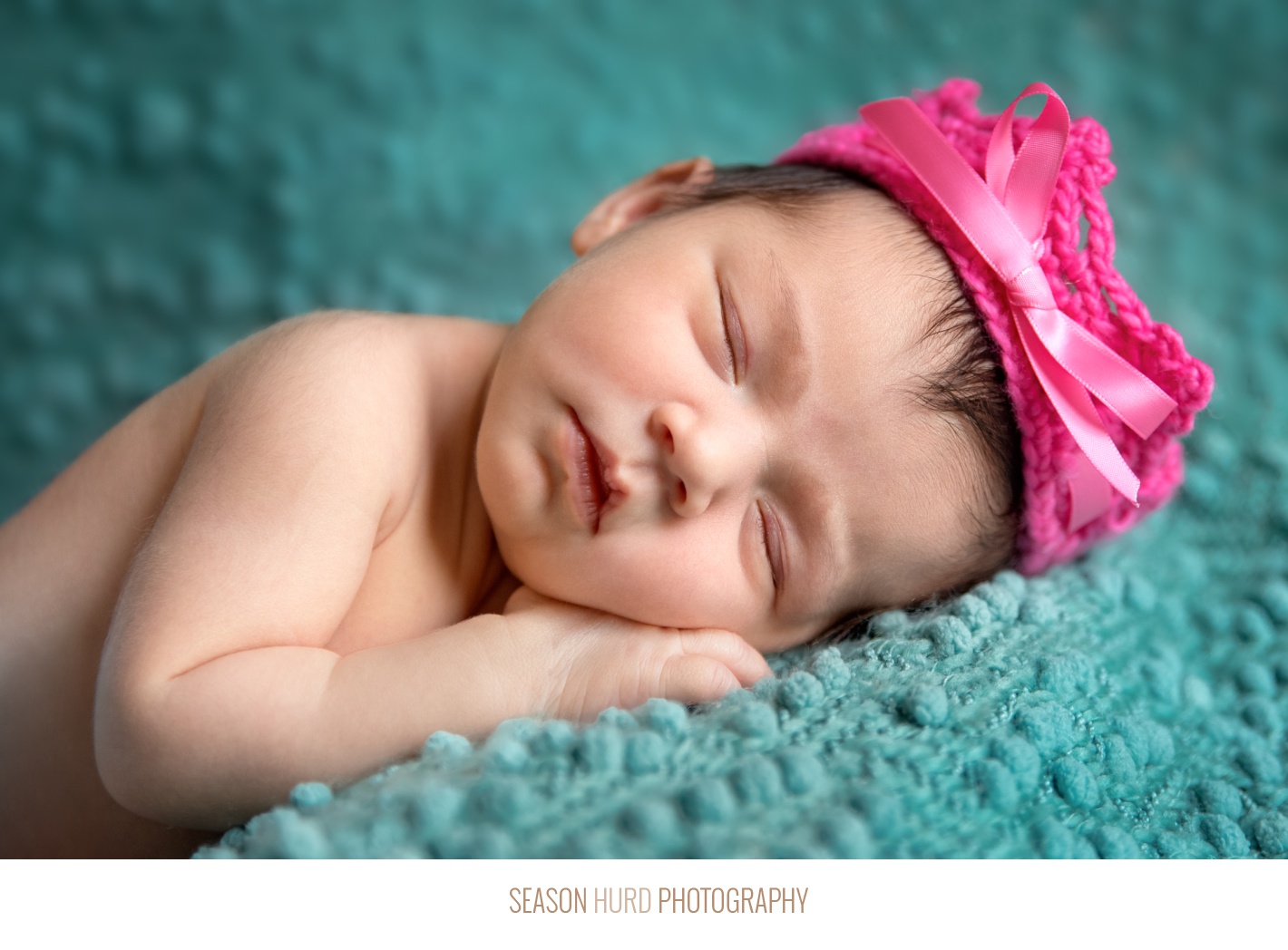 Newborn girl on teal backdrop with hot pink crochet crown